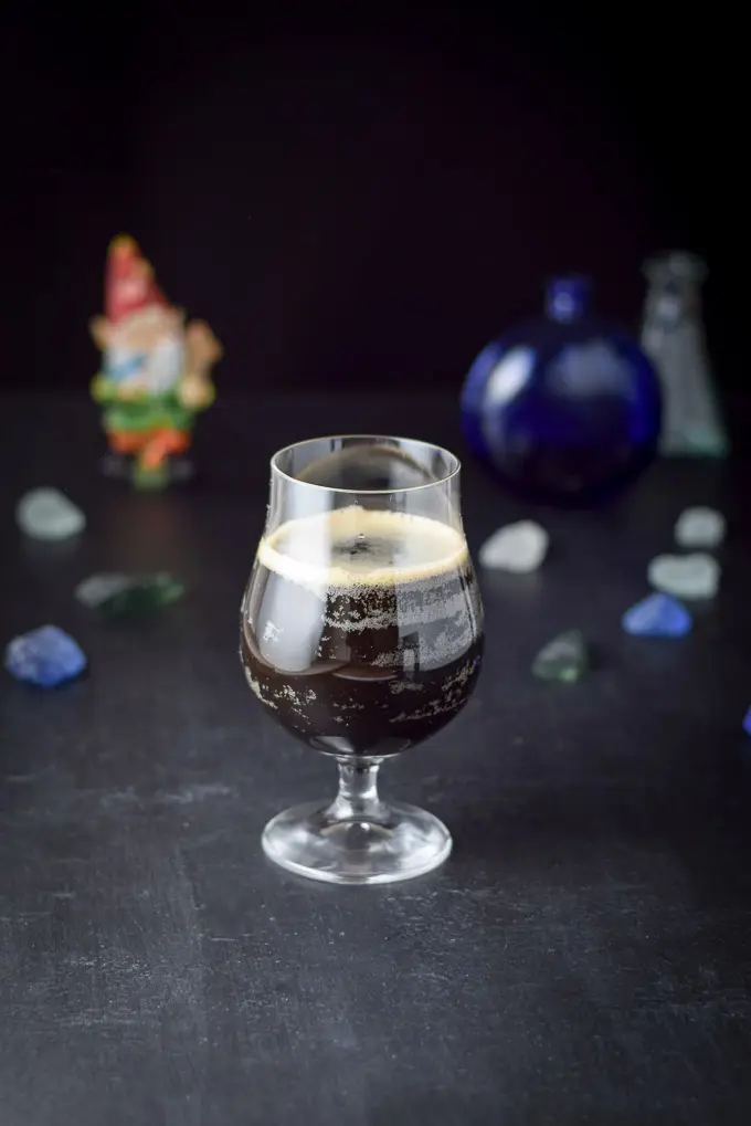 Guinness poured into the glass with the other ingredients with some rocks and glass jars in the background