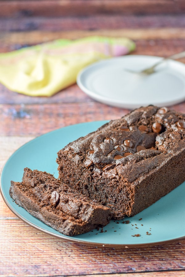 Chocolate bread sliced on a blue plate with a white plate in the background