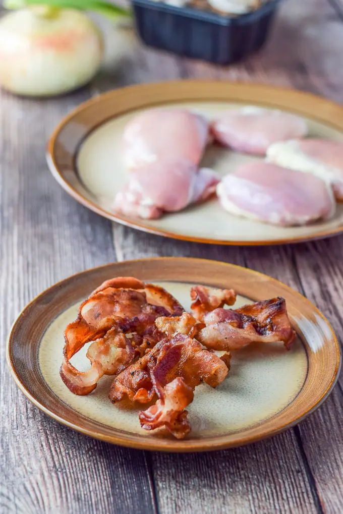 Bacon, chicken, onion and mushrooms on a wooden table