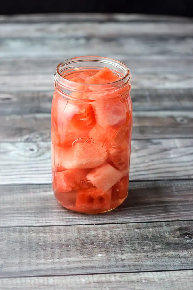 Vodka poured in the jar of watermelon on a grey table