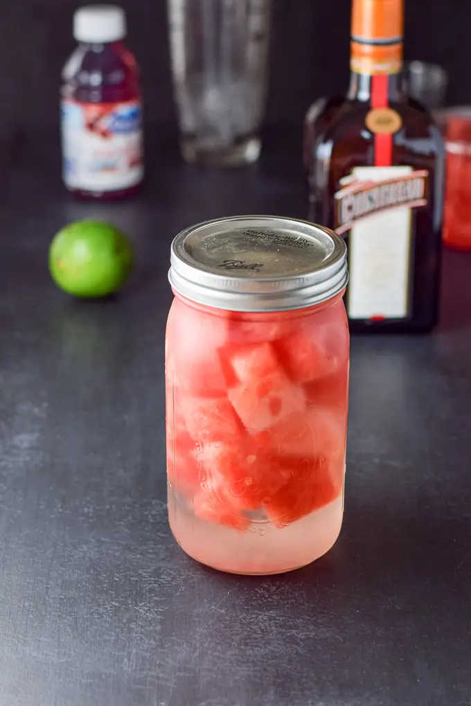 The jar of watermelon in the vodka after a week resting. There are also ingredients for a cocktail in the background