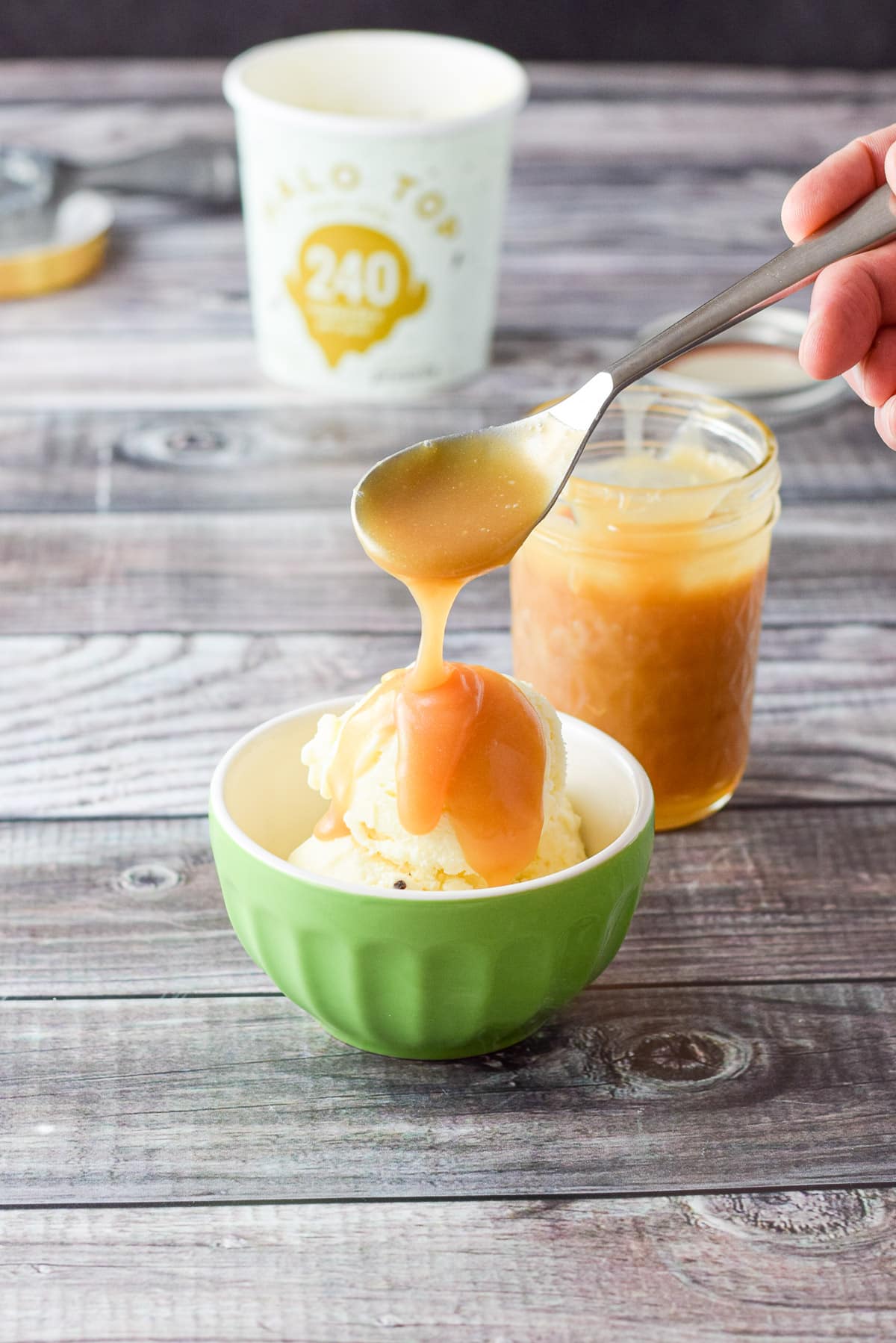 More caramel sauce poured on the ice cream with the jar in the background