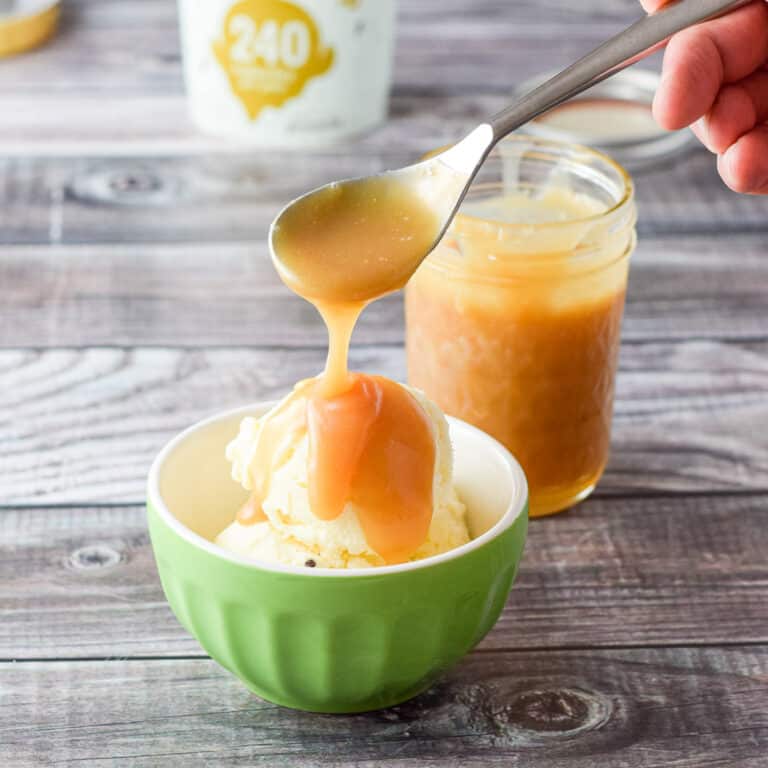 More caramel sauce poured on the ice cream with the jar in the background - square