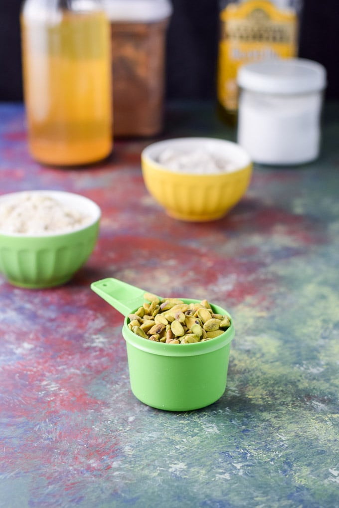 Pistachios, flour, vinegar, olive oil, baking soda and cocoa powder on a colorful table