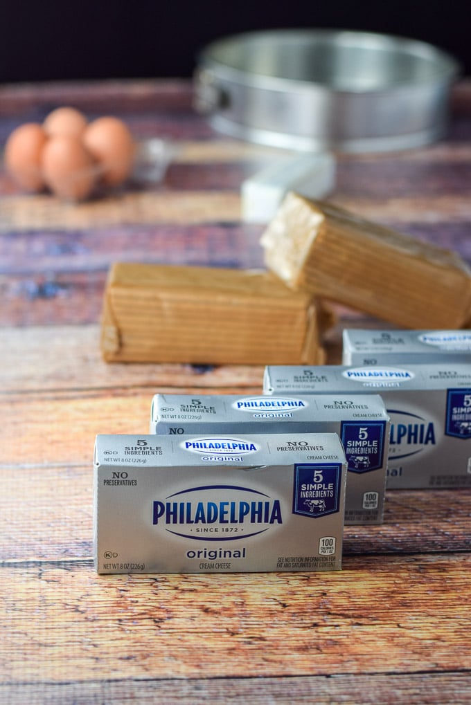Cream cheese, graham crackers, butter and eggs on a wooden table