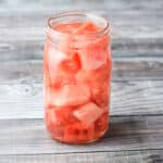 Vodka poured in the jar of watermelon on a grey table - square