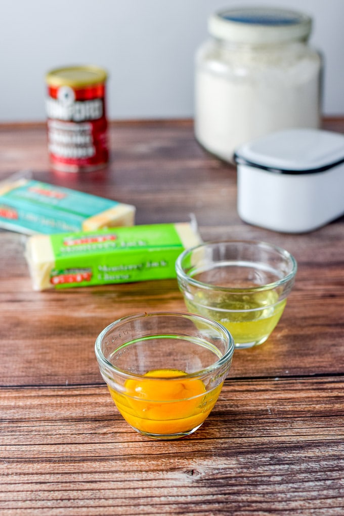 eggs separated, cheese, baking powder, flour and two packages of cheese on the table
