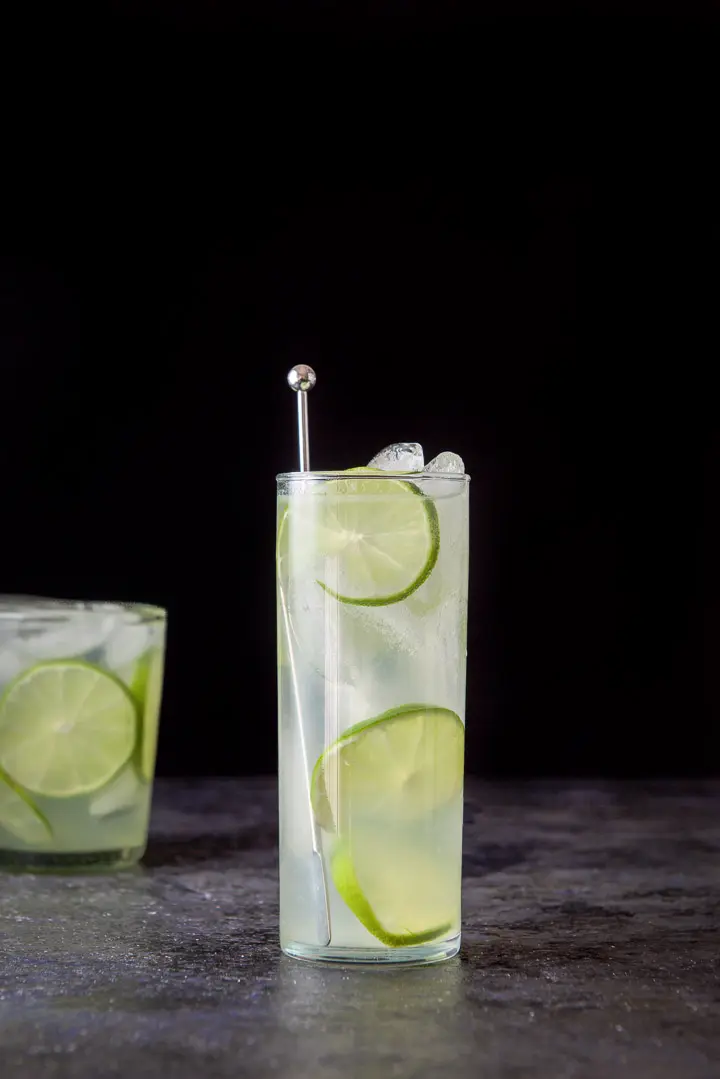 Vertical view of the tall glass filled with the lime rickey with the other glass off to the left