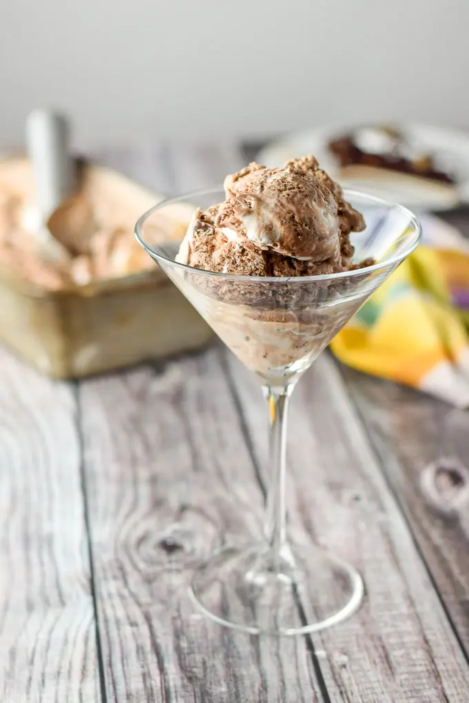 Scoops of ice cream in a martini glass with the pan of ice cream and scoop in the background