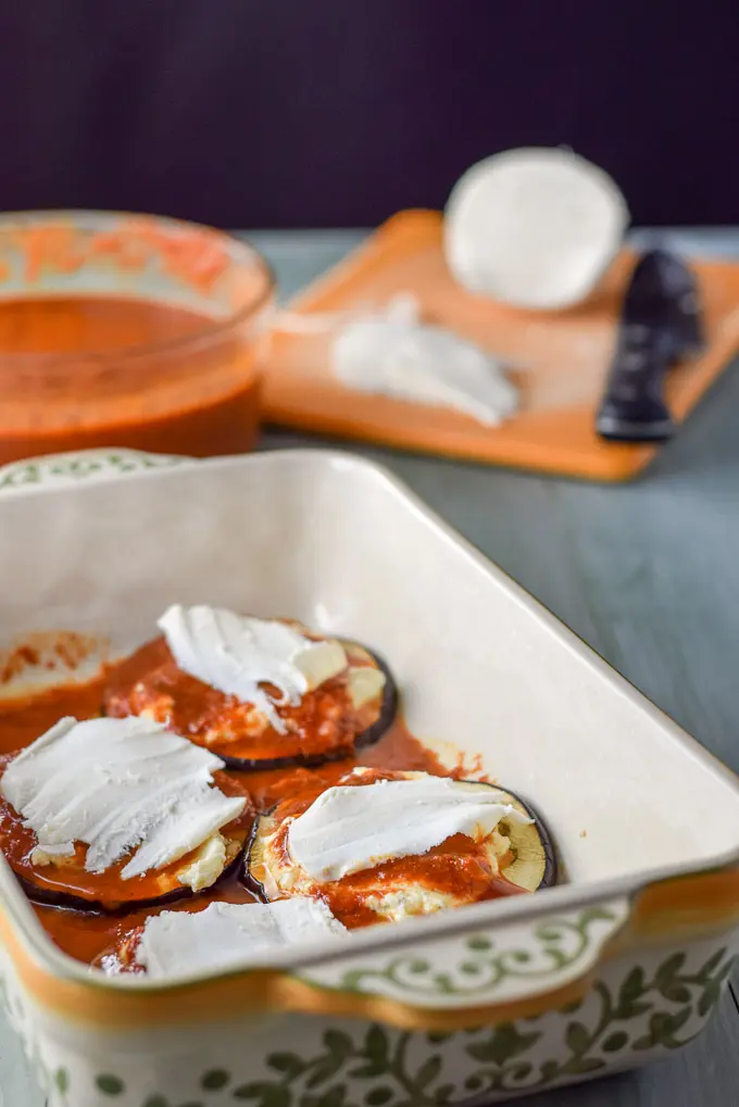 Thinly sliced mozzarella on the eggplant rounds in the baking dish