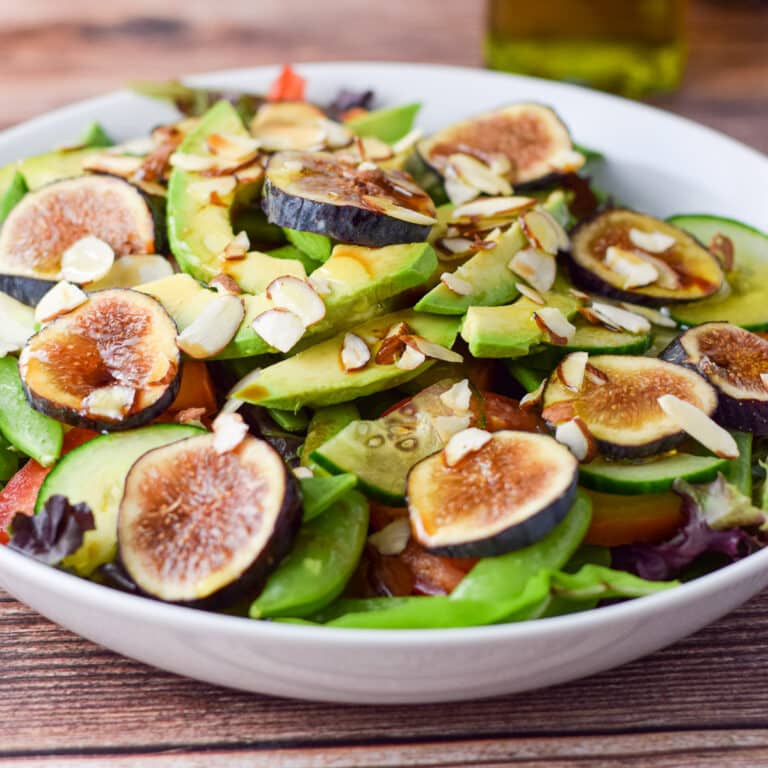 Oil and balsamic vinegar dribbled on the salad with the bottles still in the background - square
