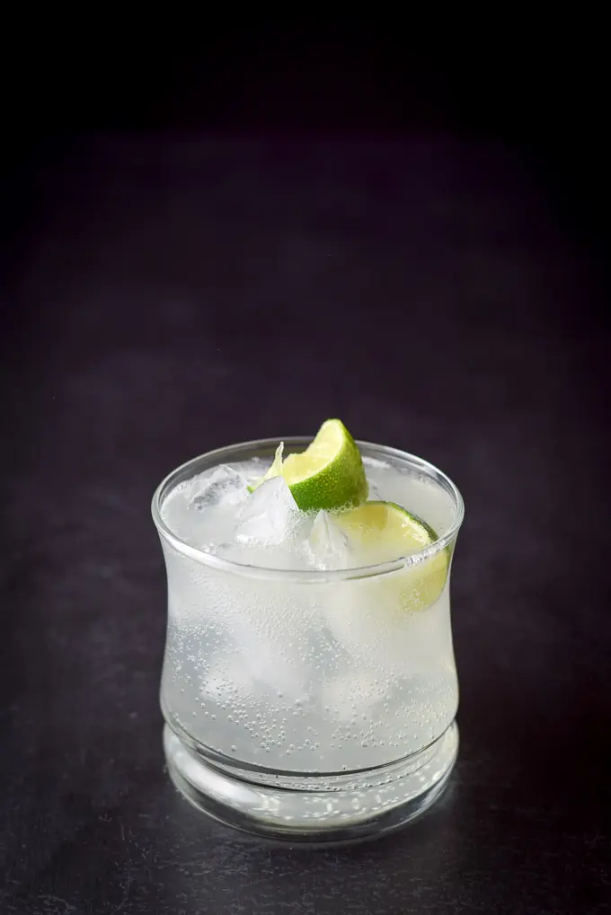 A close view of the cocktail and two lime wedges in a double old fashioned glass