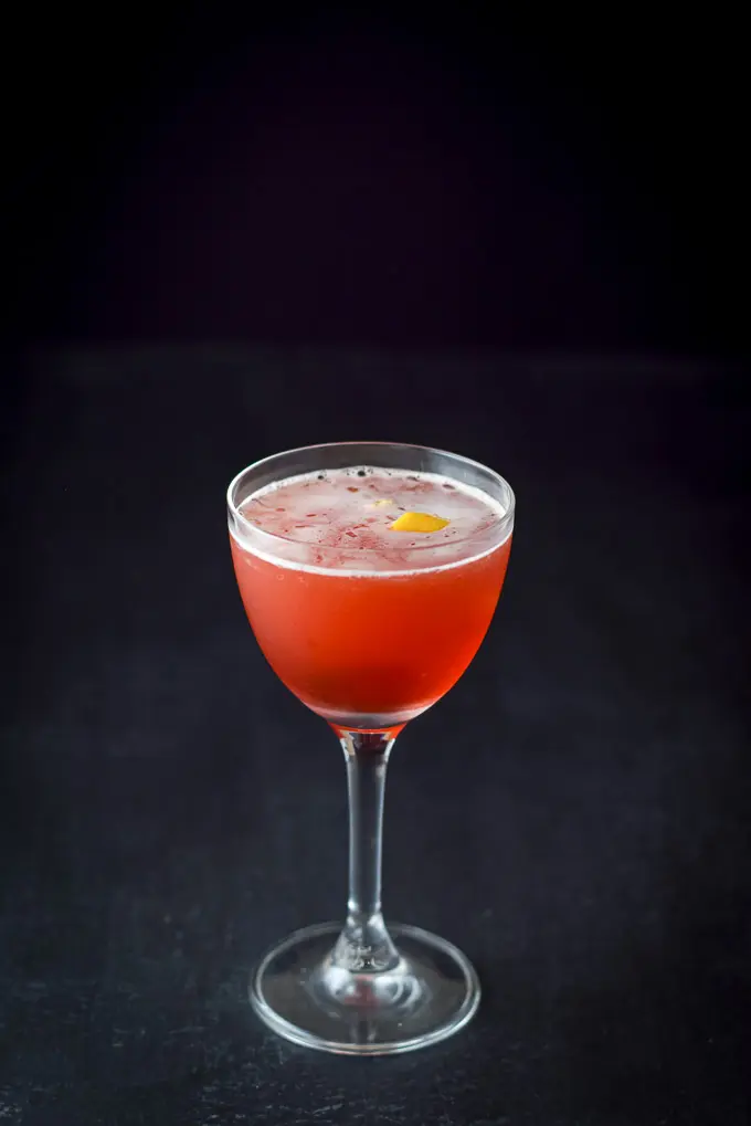 A photo of the Boulevardier with a lemon twist on a dark background
