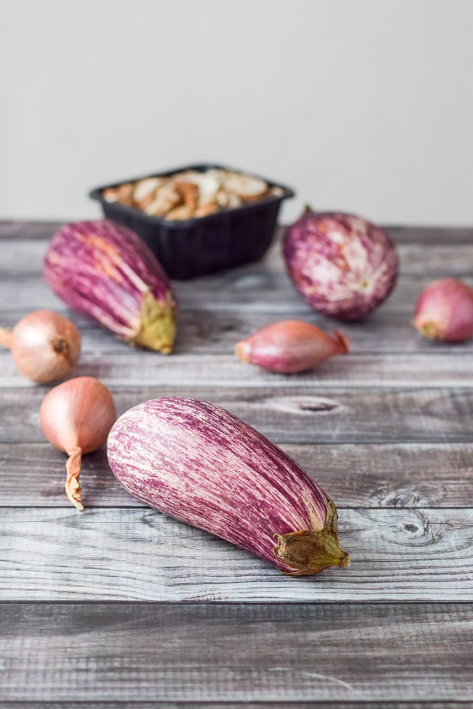 Graffiti eggplant, shallots and mushrooms on a grey table