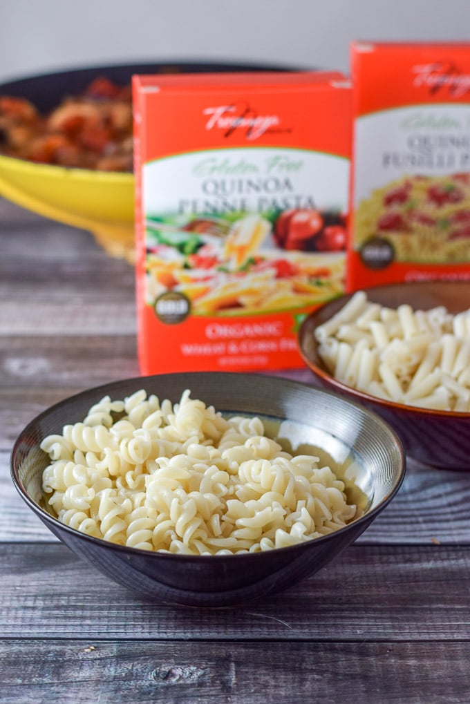 Fusilli and Penne cooked and in little bowls for with the wok in the background and boxed pasta