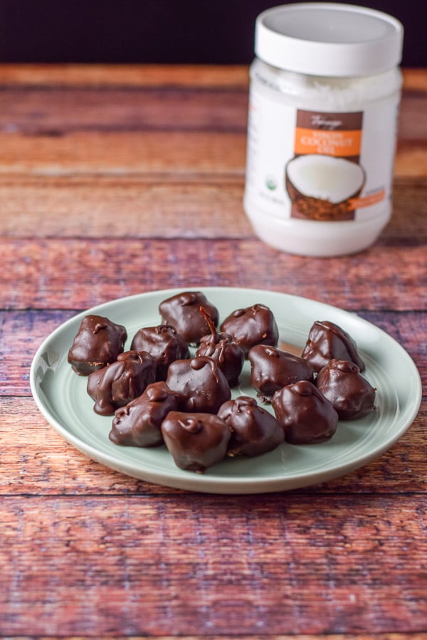 Plateful of chocolate covered coconut with a jar of coconut oil in the background.