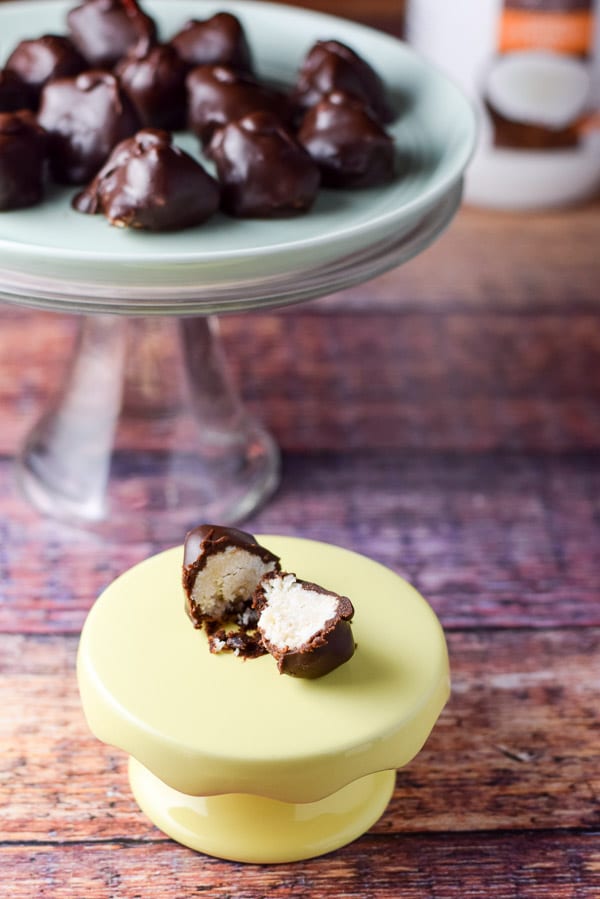 One candy cut in half and sitting on its own little pedestal, with the plateful of coconut candies on the cake stand behind it.