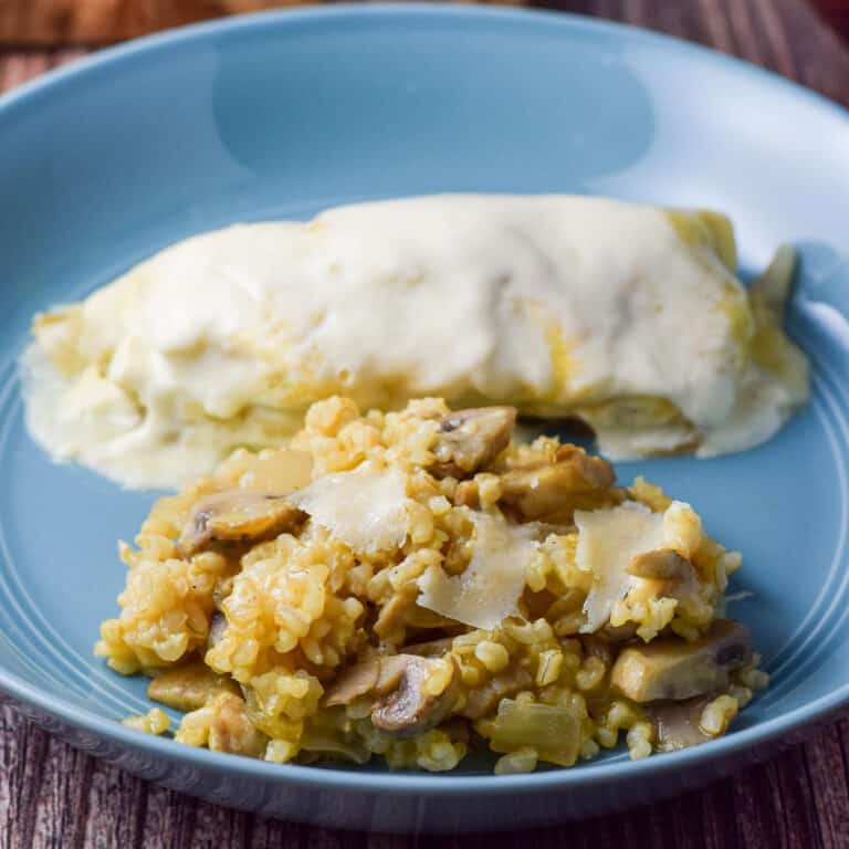A deep blue dish with rice and cheese along with an enchilada - square