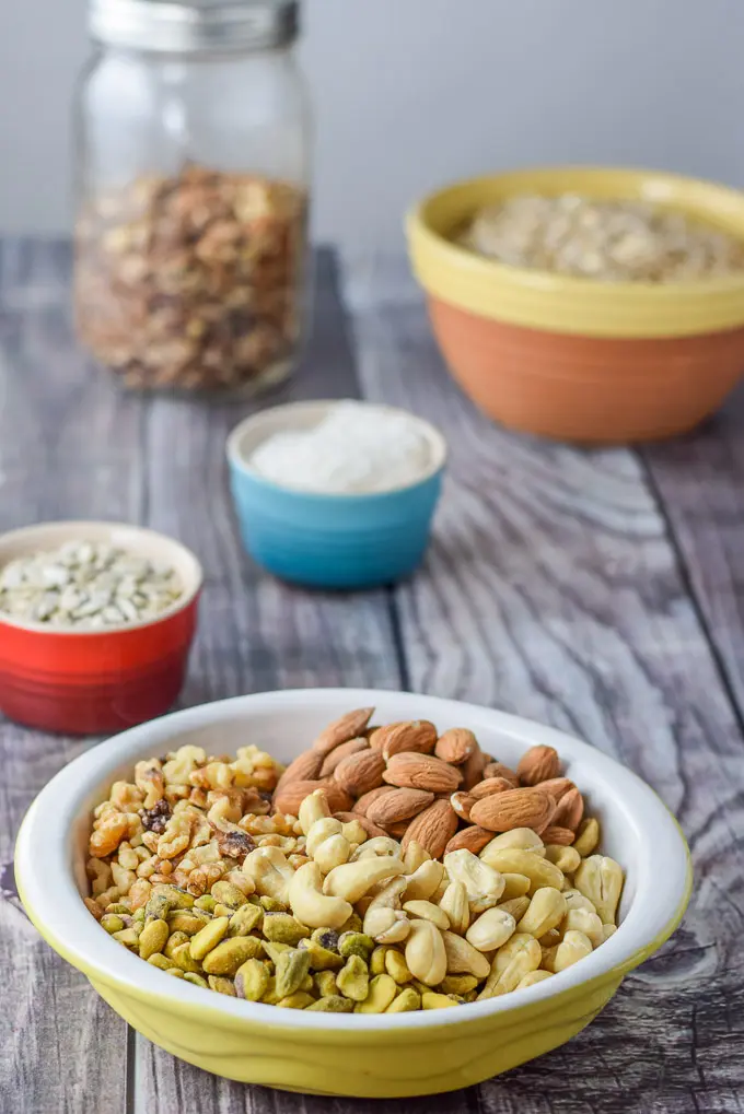 Pistachio, cashews, walnuts, almonds, sunflower seeds, coconut, pecans and oats on a grey wood background