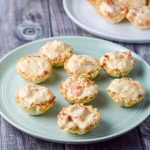 A green plate with phyllo cups filled with lobster and cream cheese - square