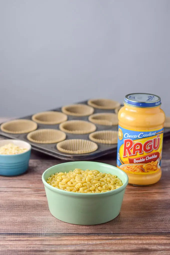 Elbow macaroni, cheddar sauce and muffin tins in the background