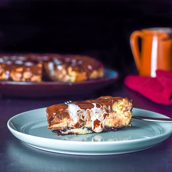 Square photo of the cheesecake with chocolate and marshmallow dripping on the plate