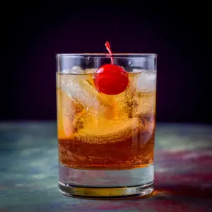 Square photo of the double old fashioned glass filled with the Manhattan with a cherry floating in it