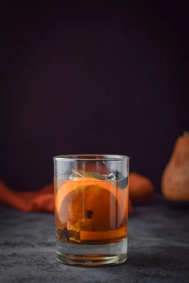 Vertical view of the classic double old fashioned glass with the cocktail and garnish in it