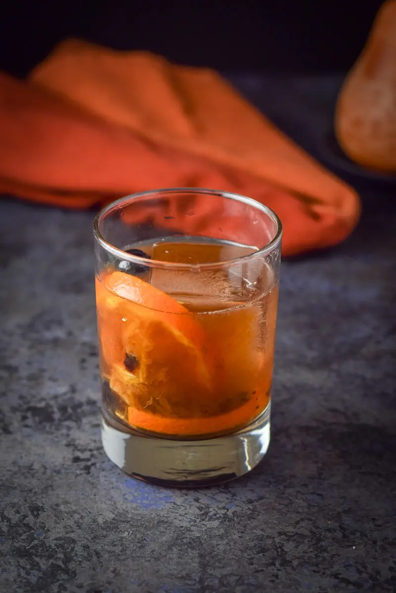 Bourbon poured in the rocks glass with a big ice cube and orange and cherries