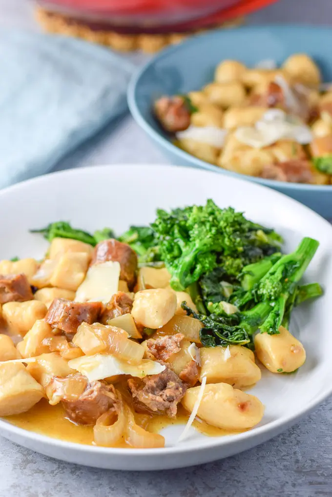 Close up of the gnocchi with sausage and butter sage sauce on a plate with broccoli rabe