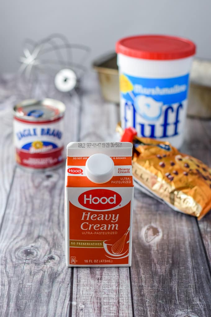 Heavy cream, condensed milk, chocolate chips, fluff and nuts on a grey table