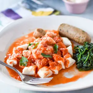 Ricotta gnocchi on a plate with a sausage and spinach