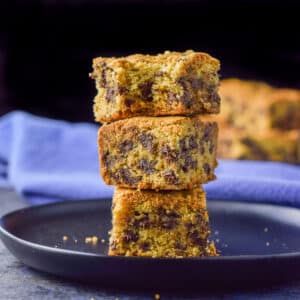 A pile of three bars with the top one with a bite taken out of it all on a black plate - square