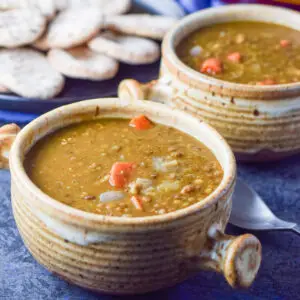 Two crocks filled with the lentil soup with pita in the background