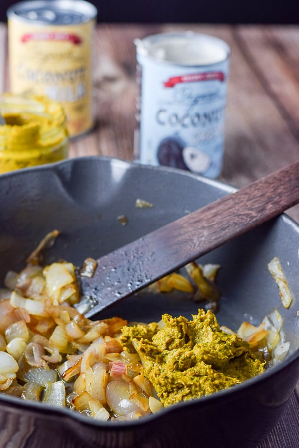 Onions and curry in a pan with coconut milk in the background