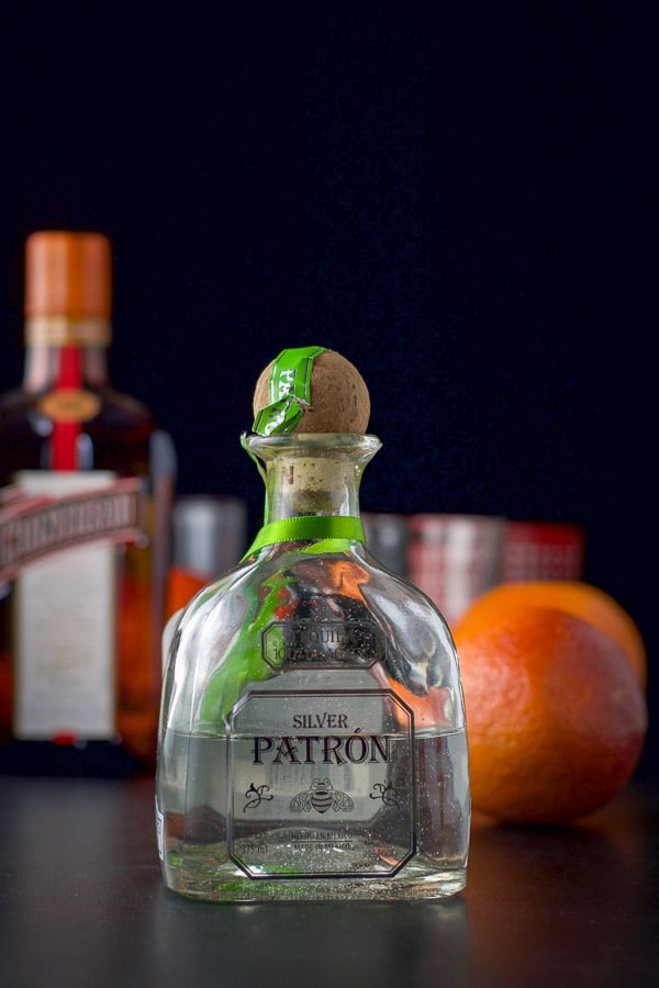 Patron silver tequila, cointreau, and blood oranges on a black table