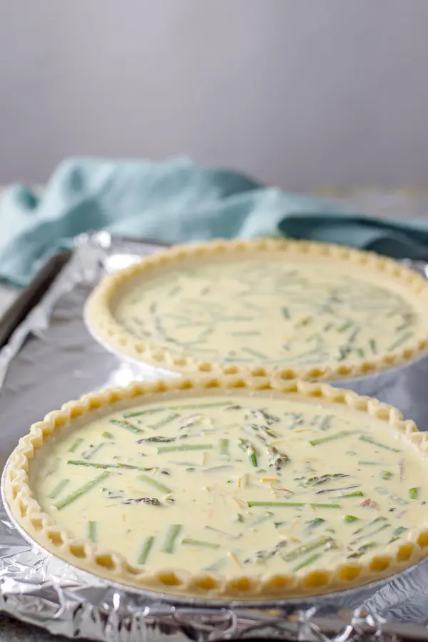 Two pie crusts filled with the quiche on a foil lined pan