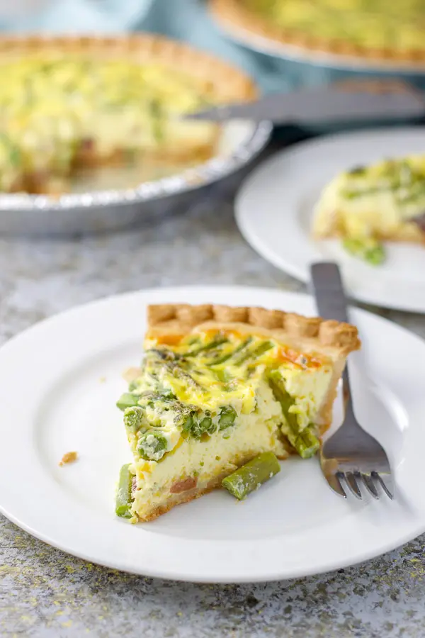 Close up of the asparagus quiche with the pans of quiches in the background
