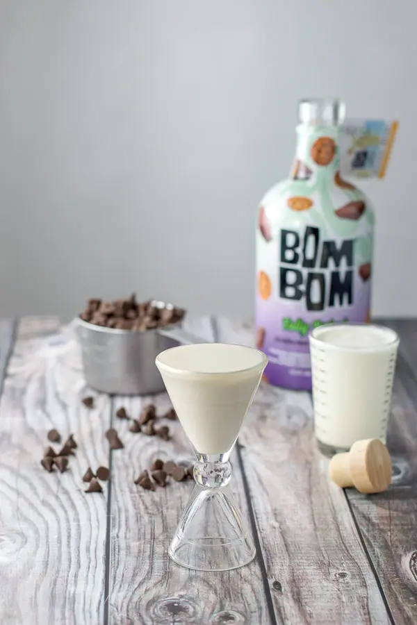 Bom Bom liqueur poured out along with the heavy cream, and chocolate chips in the background with the bottle of liquor