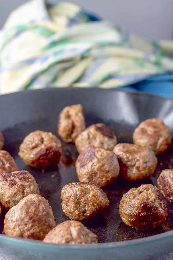 Meatballs cooked in a sauté pan with some napkins in the background