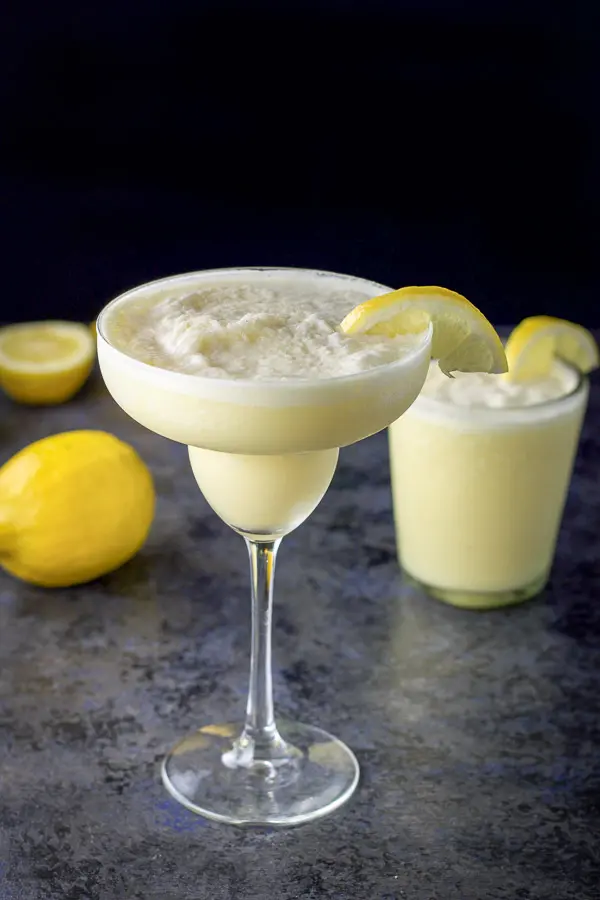 Aerial view of the lemon margarita in a classic margarita glass in front and in an old-fashioned glass in back, next to two lemons
