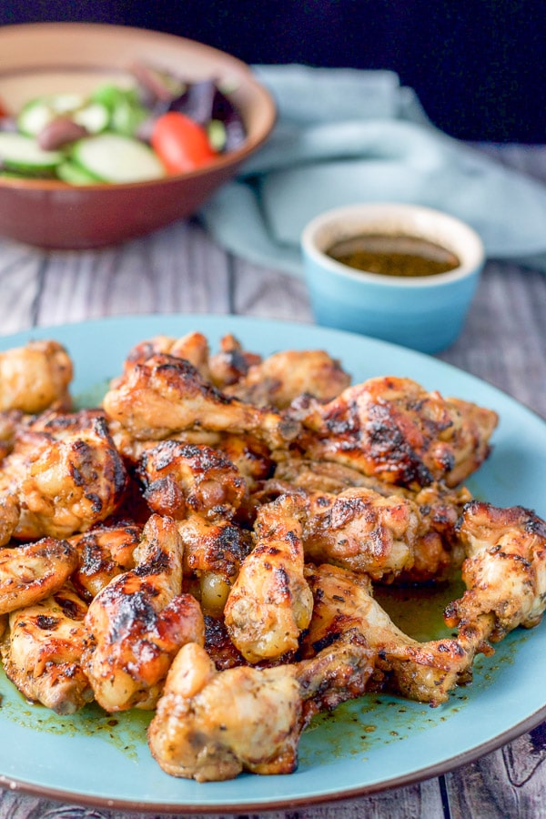 The wing out of the broiler and on a blue platter with dipping sauce in the background