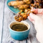 A hand holding one of the pressure cooker wings - square