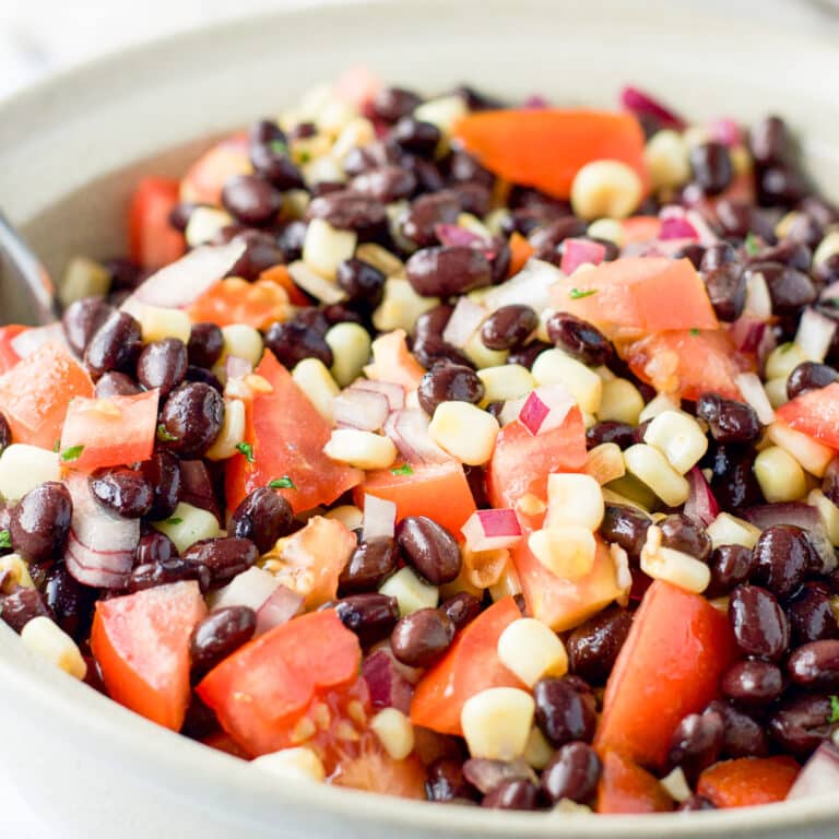 Close up of the big beige serving bowl of black beans, corn, tomatoes and onion