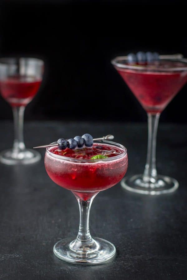 Coupe glass in front for the blueberry mint cosmo
