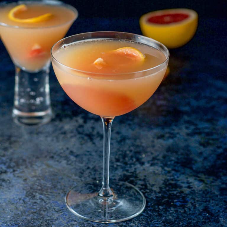 Bowl glass of the cosmo with grapefruit in it as garnish and more on the table - square