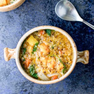 Overhead view of a crock of stew with a spoon and another partial crock - square