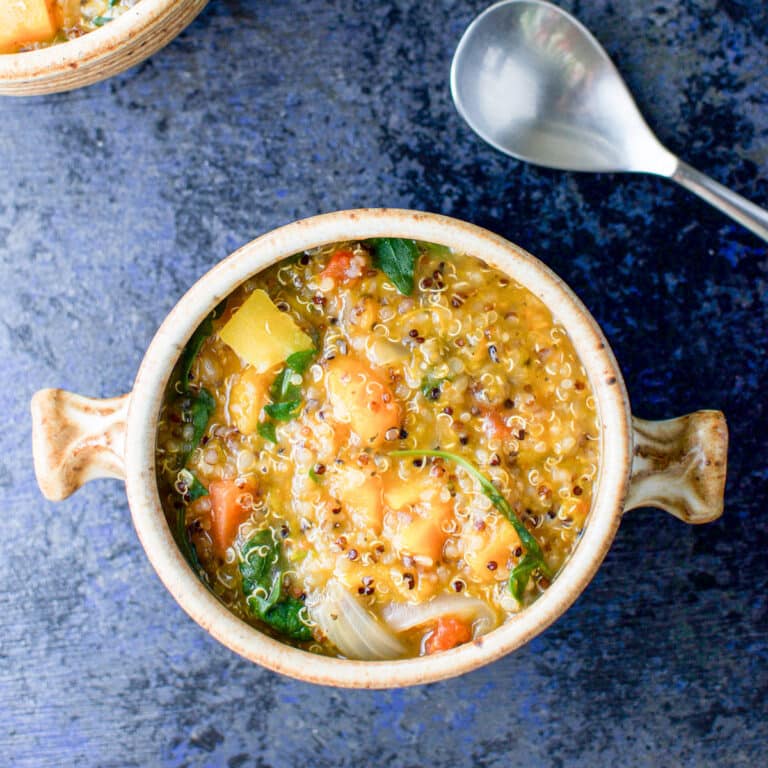 Overhead view of a crock of stew with a spoon and another partial crock - square