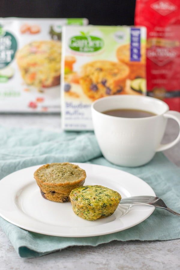 Blueberry muffin and veggie cakes with a cup of coffee and the boxes in the background