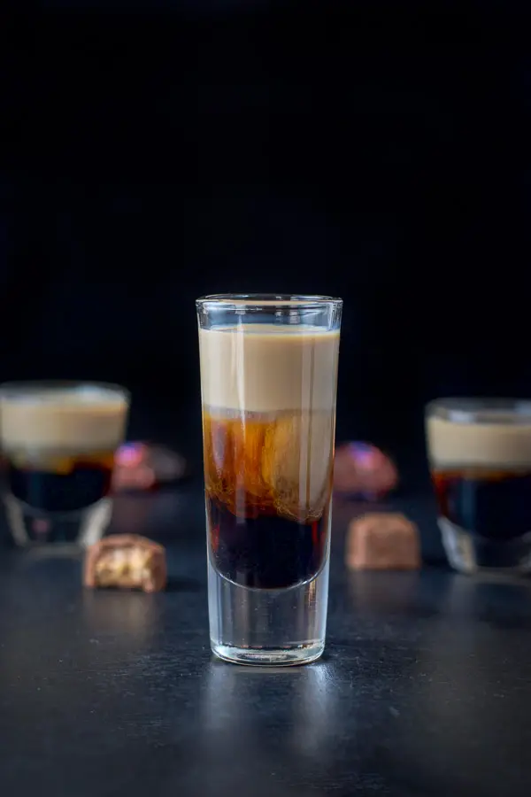 Tall glass filled with the layered shot looking delicious